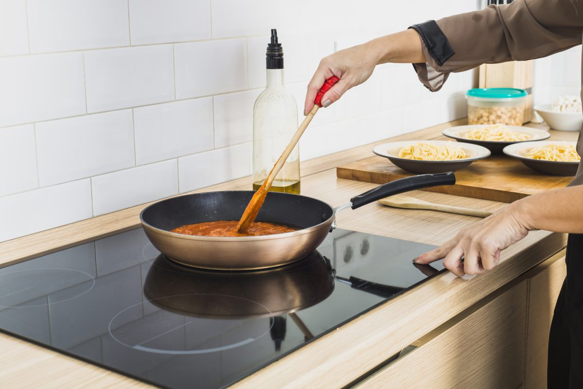 person mixing sauce pan stove 1200x800 1